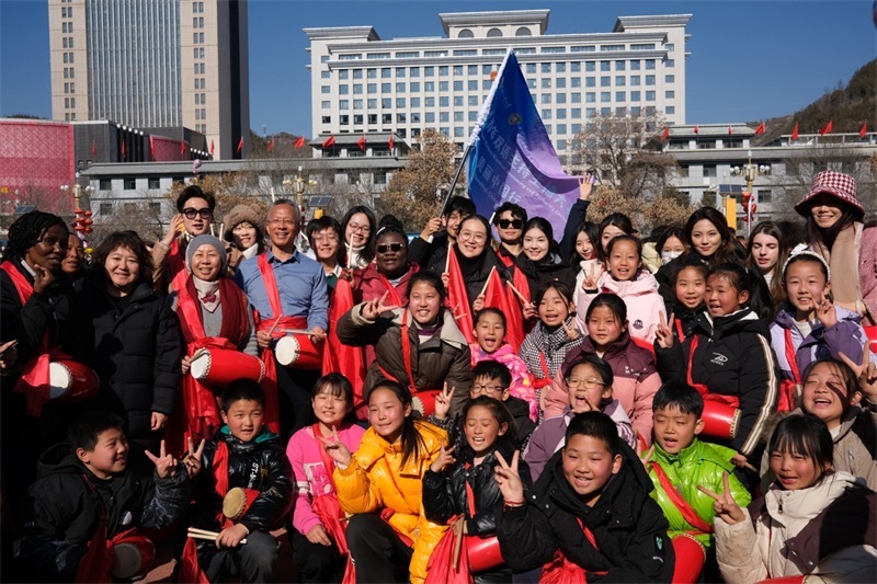 中外青年學(xué)子在安塞文化廣場(chǎng)觀看陜北腰鼓和大秧歌表演后合影留念，大家踏著鼓點(diǎn)共舞，翻飛的紅綢與躍動(dòng)的身影交織，在黃土地廣場(chǎng)上繪出一幅生動(dòng)的陜北民俗互動(dòng)畫卷