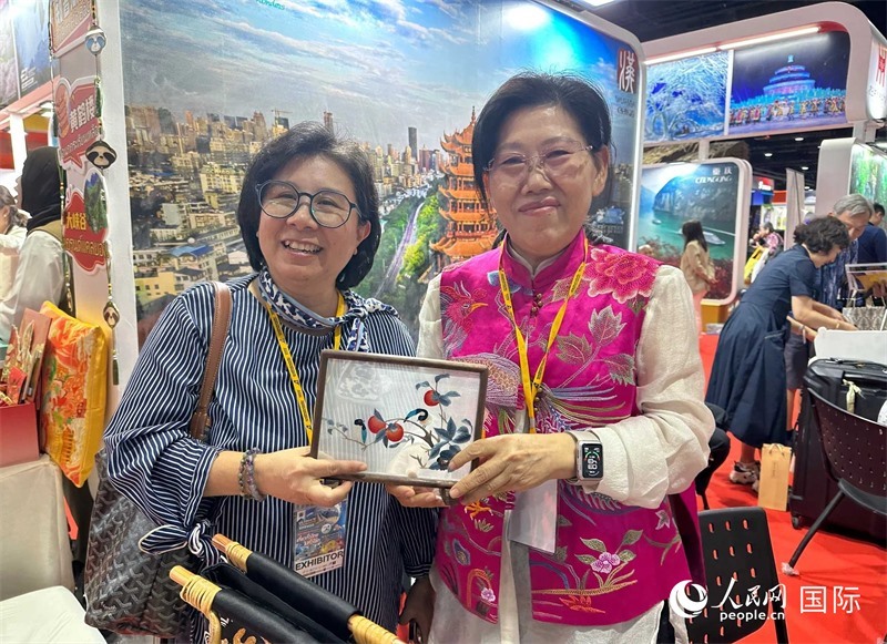 中國“大冶刺繡”傳承人劉小紅（右）參加泰國國際旅游展，向觀眾介紹中國非遺刺繡針法。人民網(wǎng)記者 簡承淵攝