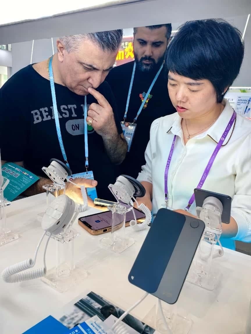 展臺工作人員向外商展示“AI TOP翻譯終端”。圖片來源：受訪者提供